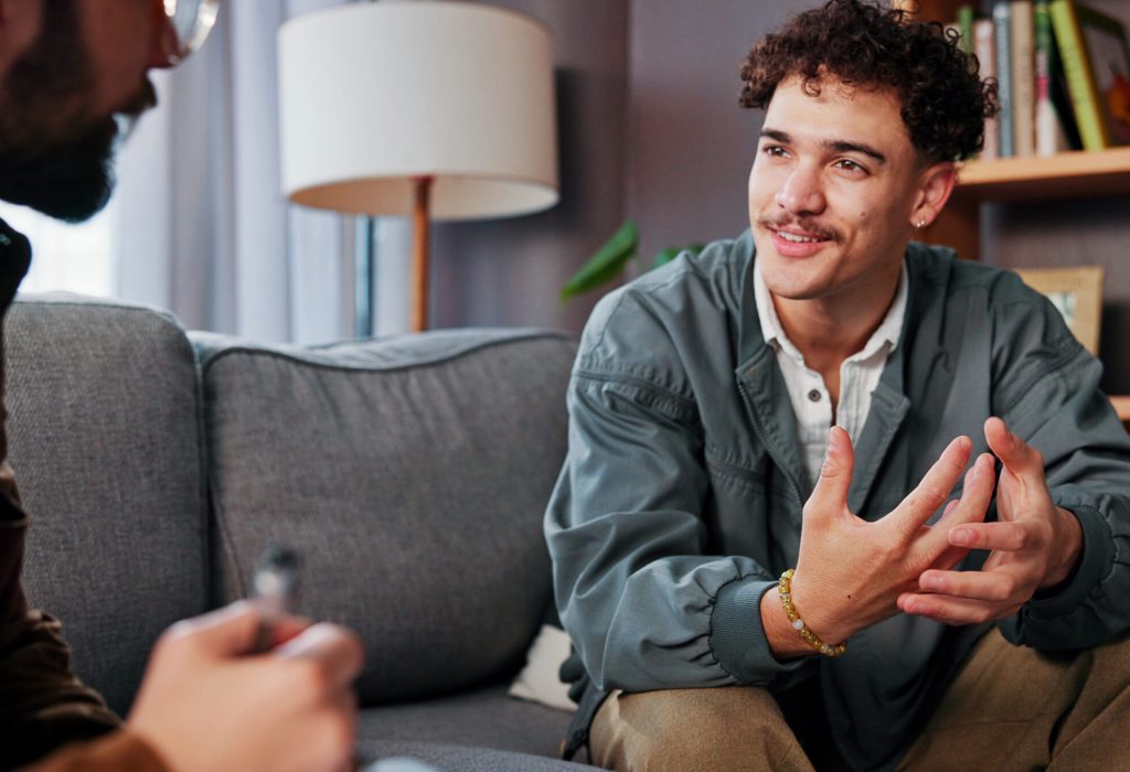 Psychology, therapist and happy man talking for help, mental health advice or support in office. Counseling session, life coach and people in therapy for assessment, consultation and evaluation.